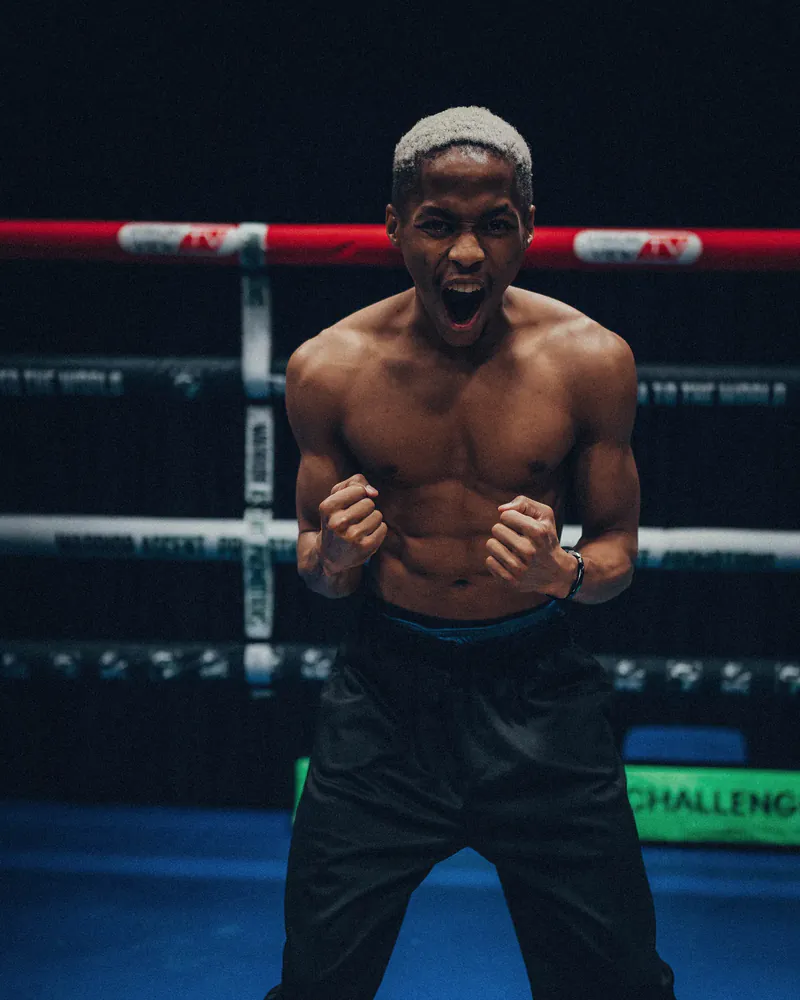 Mpendulo Msimanga stands in a boxing ring with both fists raised
