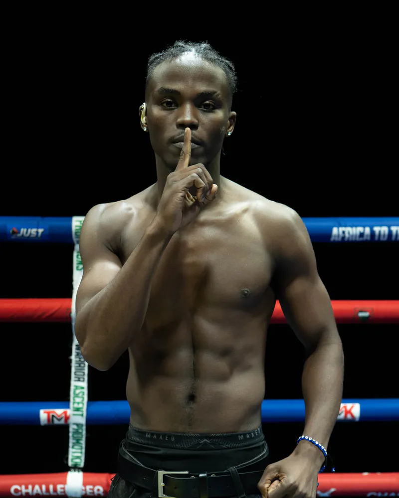 Owen Venganayi holds one finger to his lips inside the boxing ring