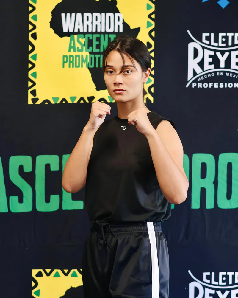 Saarah Karriem stands with both fists raised before a Warrior Ascent backdrop