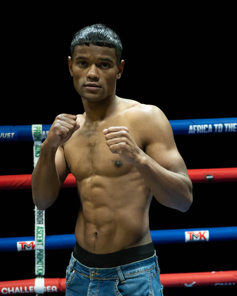 Shameeg Williams stands with both fists raised inside the boxing ring