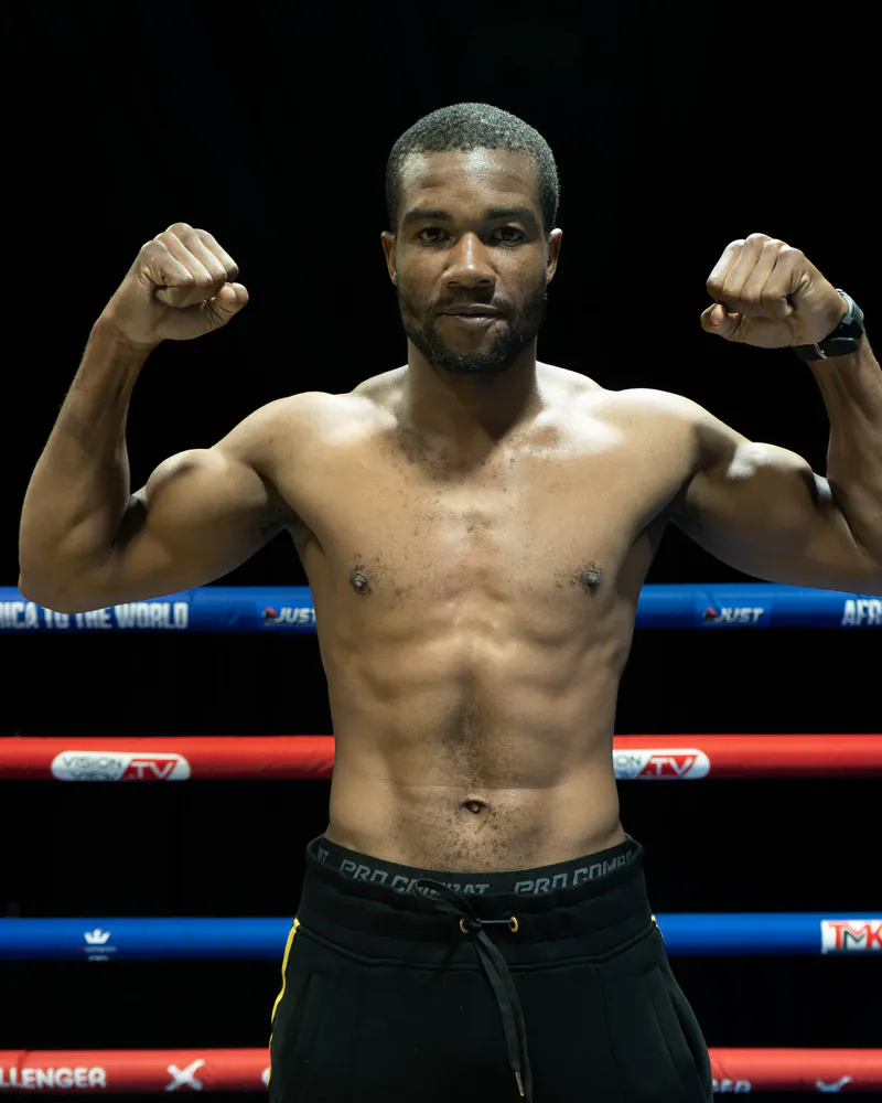 Tendai Sinakoma flexes both arms inside the boxing ring