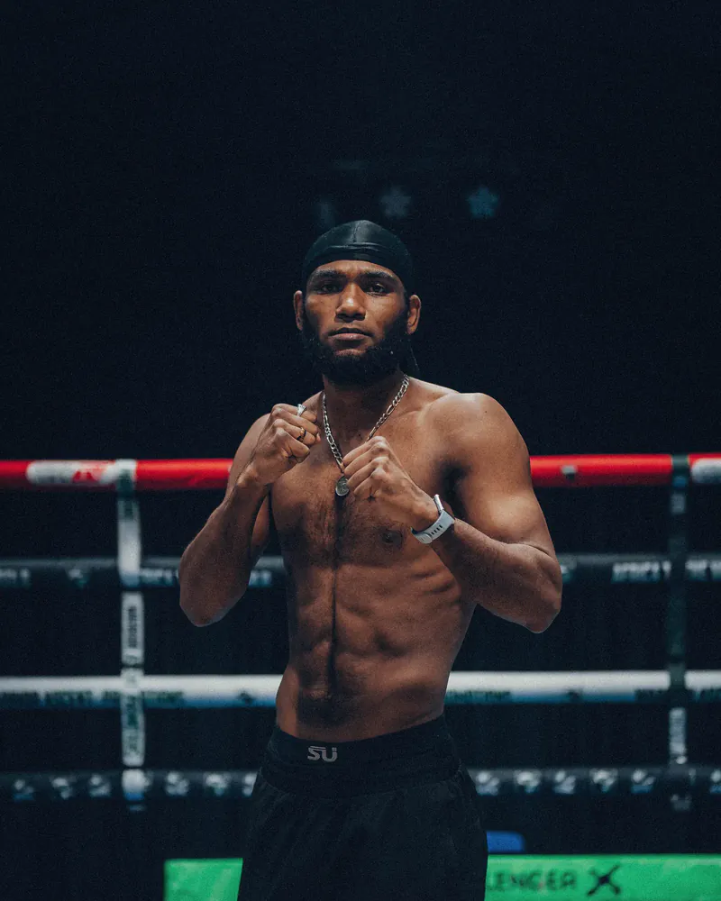 Wasim Chellan poses with his fists raised inside a boxing ring